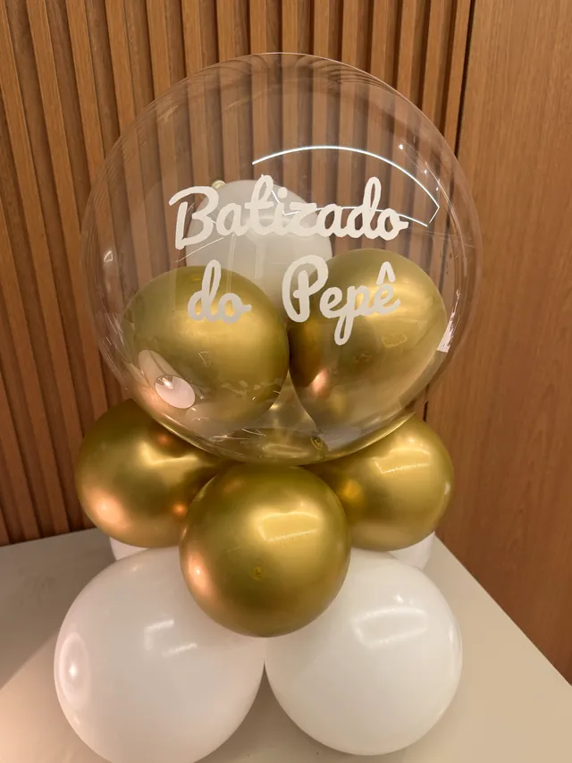 Arranjo de mesa com balões dourados cromados e brancos e balão bubble personalizado escrito Batizado do Pepê, feito à mão pelo Ateliê Balonê em São Paulo